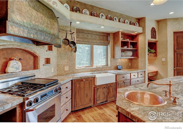 kitchen featuring stainless steel range, sink, light hardwood / wood-style flooring, and range hood