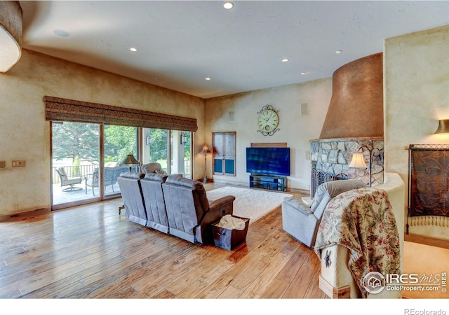 living room with a stone fireplace and light hardwood / wood-style flooring