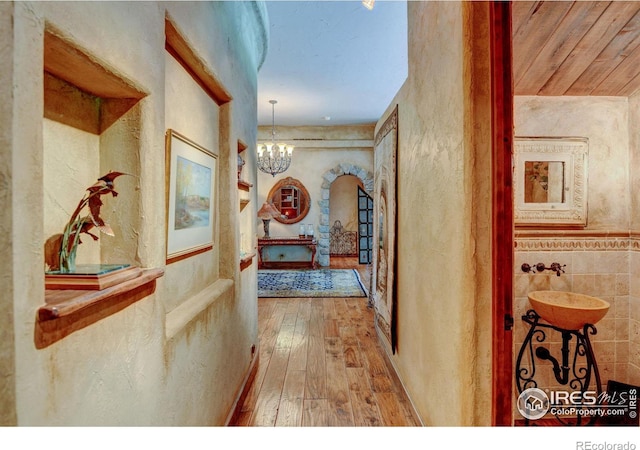 hallway with sink, a chandelier, and hardwood / wood-style flooring