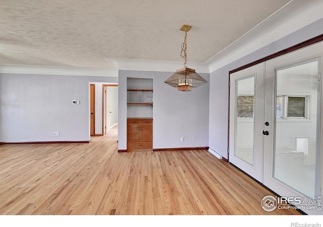 empty room featuring hardwood / wood-style flooring, a textured ceiling, and french doors