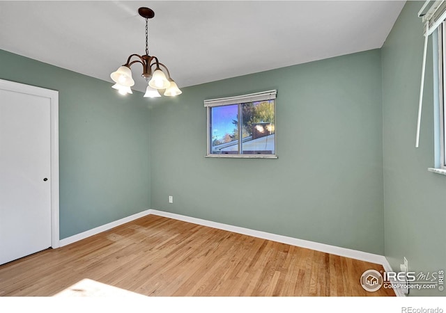 spare room with a chandelier and hardwood / wood-style floors