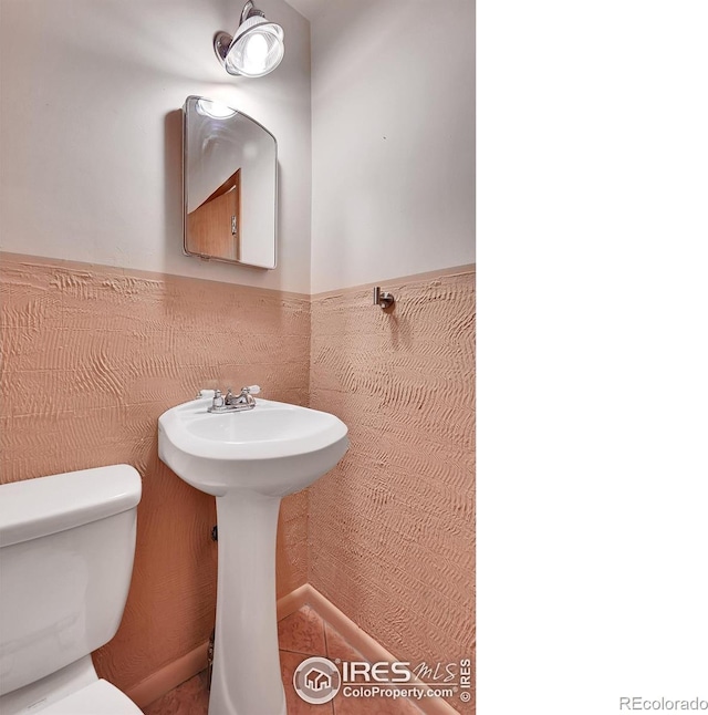 bathroom featuring tile walls and toilet