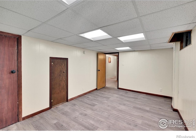 unfurnished room with a paneled ceiling and light wood-type flooring