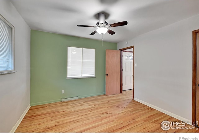 empty room with ceiling fan and light hardwood / wood-style floors