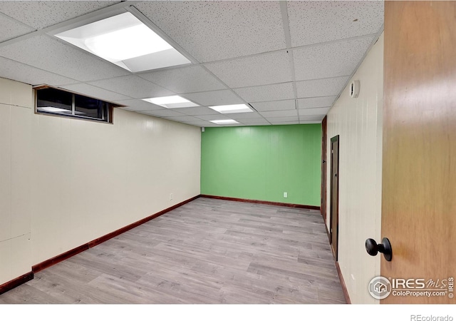 basement featuring a paneled ceiling and light wood-type flooring