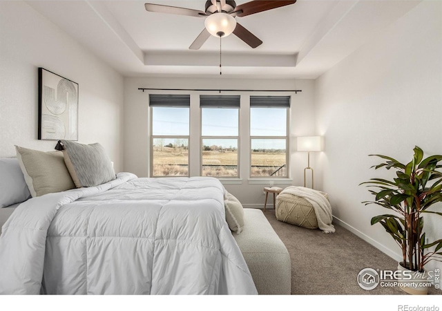 carpeted bedroom featuring a tray ceiling and ceiling fan