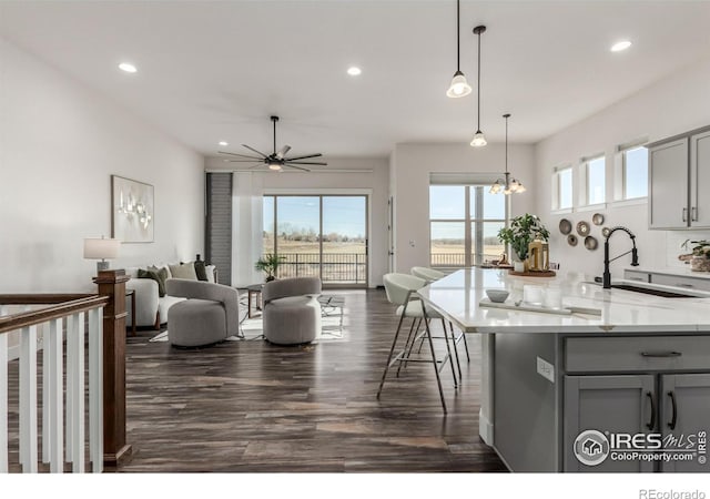 kitchen featuring light stone countertops, ceiling fan, dark hardwood / wood-style floors, decorative light fixtures, and gray cabinets