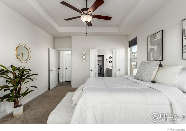 carpeted bedroom with ceiling fan, connected bathroom, and a tray ceiling