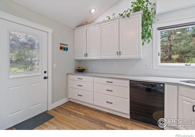 kitchen with white cabinetry, light hardwood / wood-style flooring, vaulted ceiling, and black dishwasher