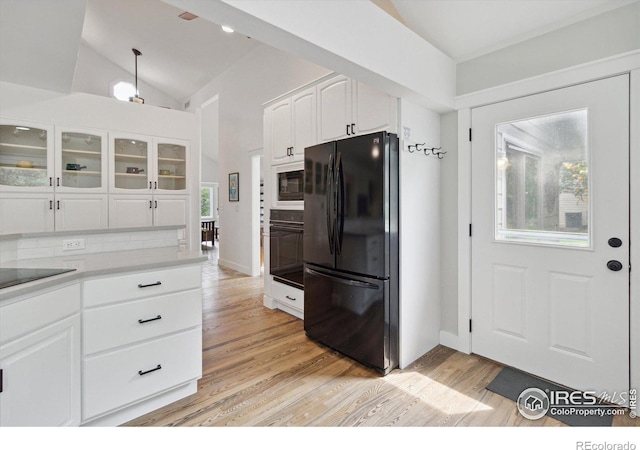 kitchen featuring backsplash, black appliances, white cabinets, vaulted ceiling, and light wood-type flooring