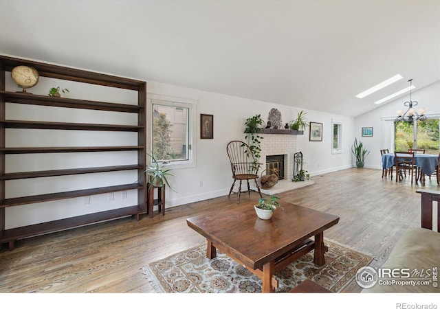 living room with hardwood / wood-style floors, lofted ceiling with skylight, and a notable chandelier