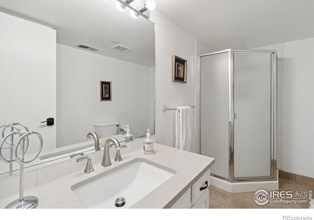 bathroom featuring tile patterned floors, vanity, toilet, and walk in shower