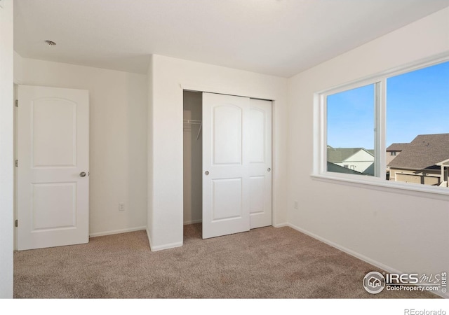 unfurnished bedroom featuring light carpet and a closet