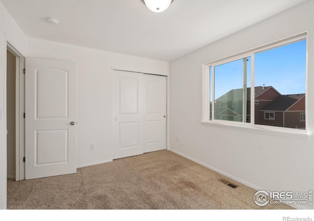 unfurnished bedroom with a closet and light colored carpet