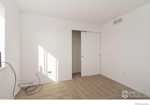 unfurnished bedroom featuring light carpet and a closet