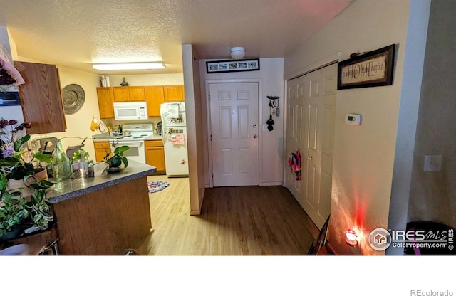 kitchen featuring light hardwood / wood-style floors, white appliances, and a textured ceiling