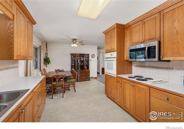 kitchen with ceiling fan, sink, white appliances, and backsplash