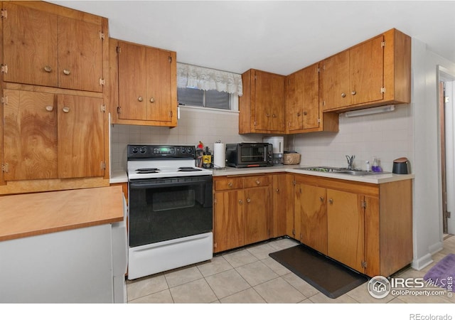 kitchen with white range with electric cooktop, decorative backsplash, sink, and light tile patterned flooring