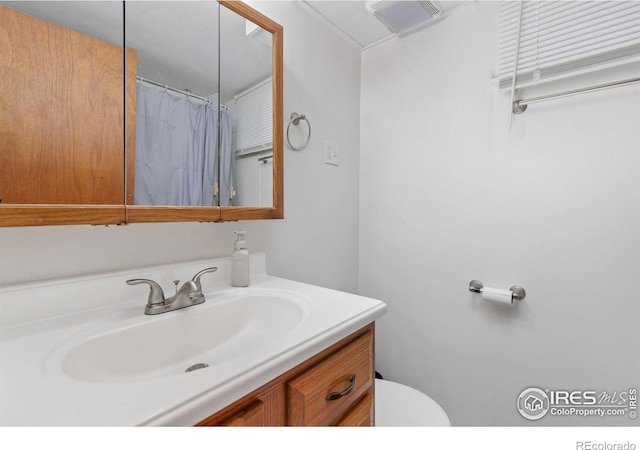 bathroom with curtained shower, vanity, and toilet