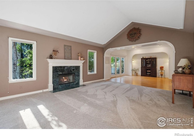 living room featuring carpet, a high end fireplace, and lofted ceiling