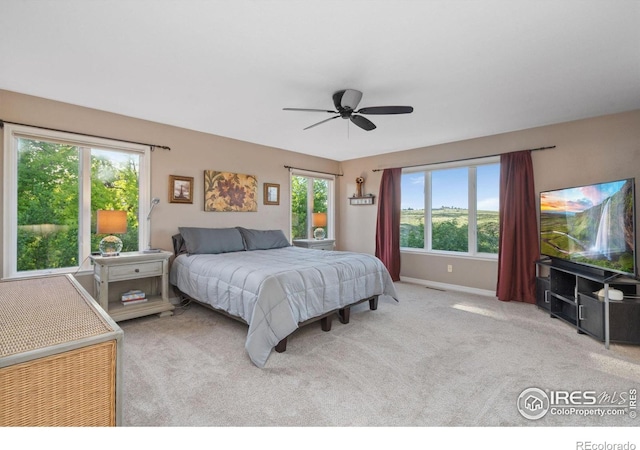 bedroom with ceiling fan, light carpet, and multiple windows