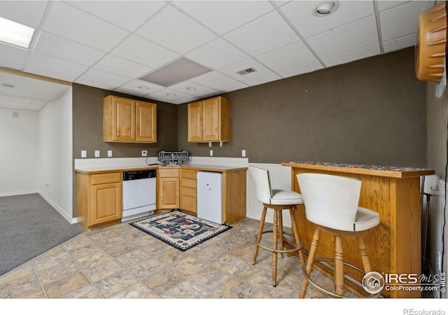 kitchen with dishwasher, a drop ceiling, kitchen peninsula, and a breakfast bar