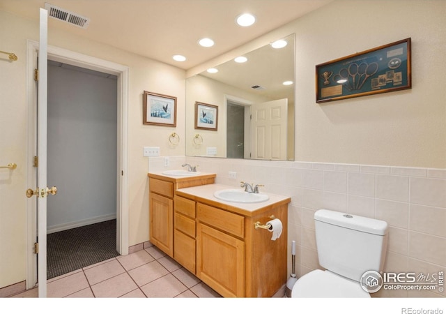 bathroom with tile patterned flooring, vanity, toilet, and tile walls