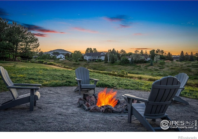 patio terrace at dusk featuring a lawn and an outdoor fire pit