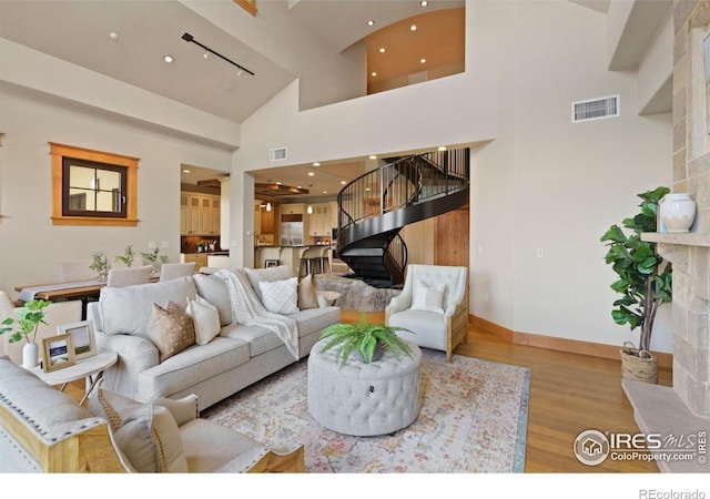 living room with a fireplace, light hardwood / wood-style flooring, and high vaulted ceiling