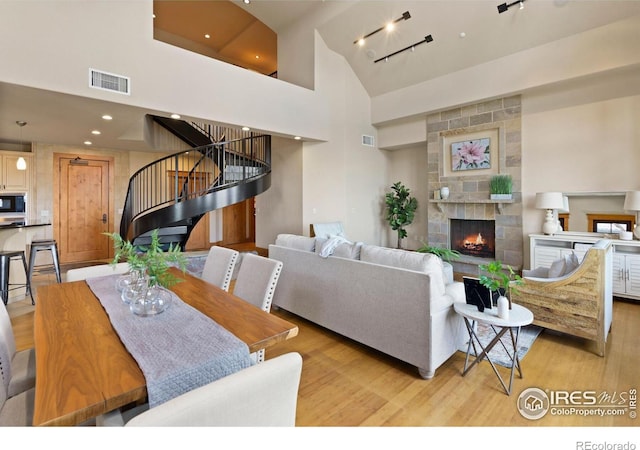 dining area featuring a fireplace, track lighting, a high ceiling, and light wood-type flooring