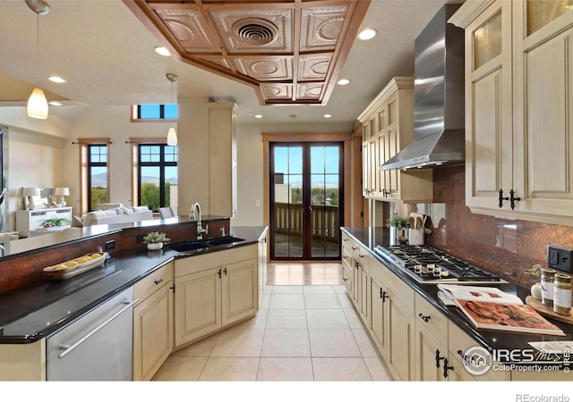 kitchen featuring appliances with stainless steel finishes, wall chimney exhaust hood, sink, cream cabinets, and light tile patterned flooring