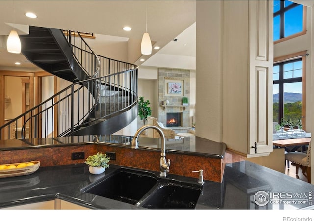 kitchen featuring a fireplace, a mountain view, hanging light fixtures, and sink