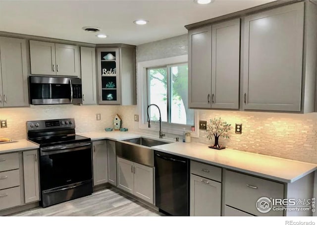 kitchen with gray cabinets, decorative backsplash, sink, and black appliances