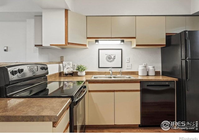 kitchen with cream cabinets, black appliances, and sink