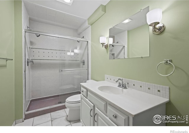 bathroom with tile patterned floors, a shower with door, vanity, and toilet