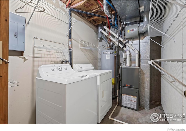 clothes washing area with electric panel, water heater, and washing machine and dryer