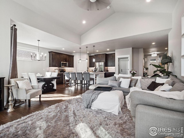 living room featuring dark hardwood / wood-style floors, ceiling fan with notable chandelier, and high vaulted ceiling