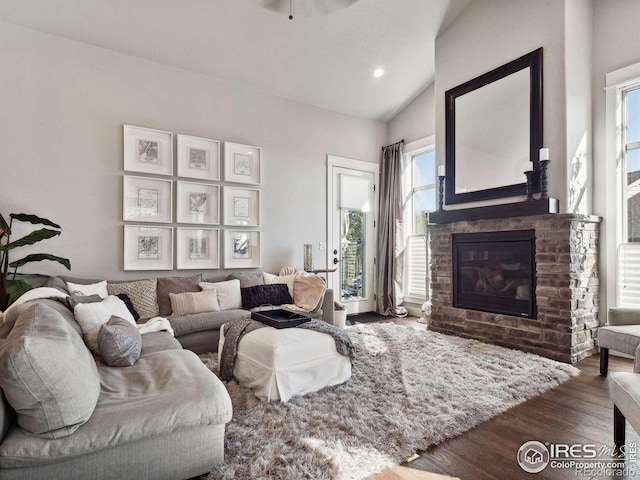 living room with ceiling fan, dark wood-type flooring, a fireplace, and vaulted ceiling