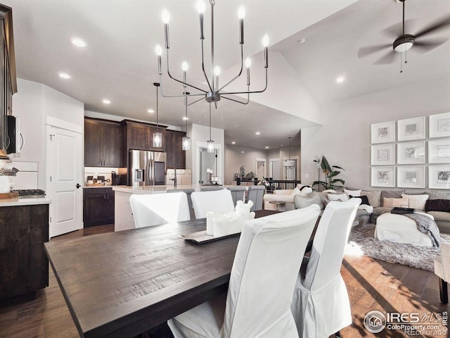 dining space featuring ceiling fan with notable chandelier, dark wood-type flooring, and high vaulted ceiling