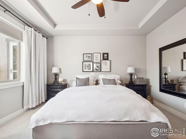 carpeted bedroom featuring a raised ceiling and ceiling fan