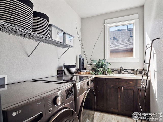 clothes washing area featuring washer and dryer, cabinets, light wood-type flooring, and sink