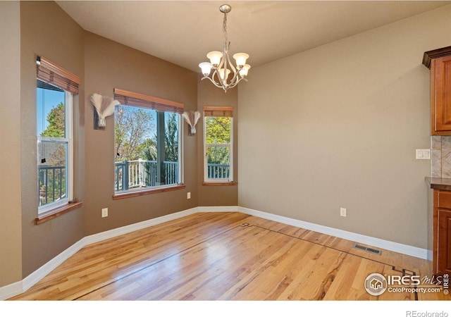 unfurnished dining area featuring light hardwood / wood-style flooring and a chandelier