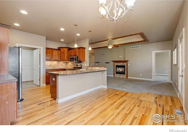 kitchen with kitchen peninsula, pendant lighting, stainless steel appliances, and light hardwood / wood-style floors