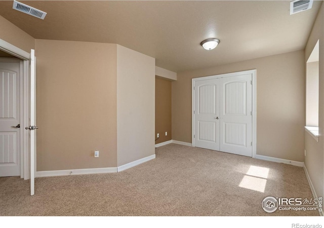 unfurnished bedroom featuring light colored carpet and a closet