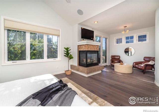 living room featuring a tile fireplace, hardwood / wood-style floors, a chandelier, and lofted ceiling