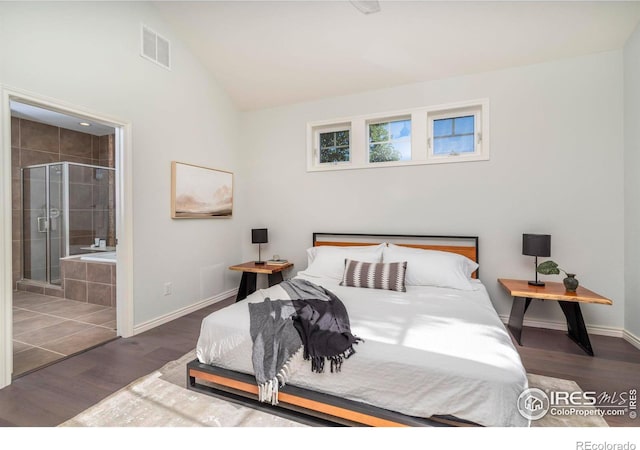 bedroom featuring dark hardwood / wood-style flooring, lofted ceiling, and connected bathroom