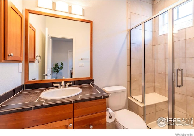 bathroom featuring vanity, toilet, and a shower with shower door