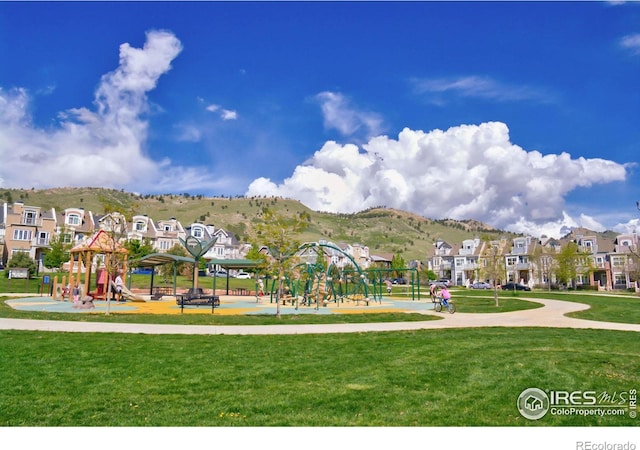 view of property's community with a playground, a mountain view, and a yard