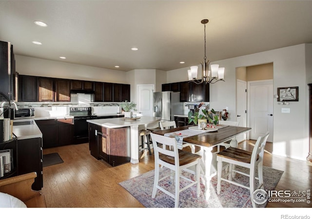 kitchen with decorative light fixtures, a kitchen island, dark brown cabinets, and stainless steel appliances