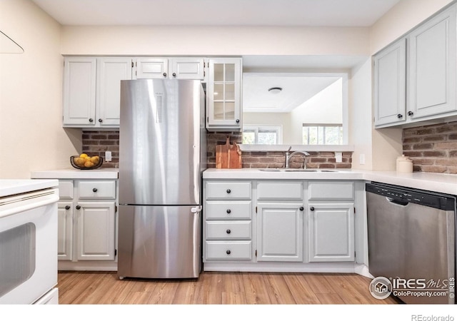 kitchen with a sink, stainless steel appliances, light wood-type flooring, and light countertops